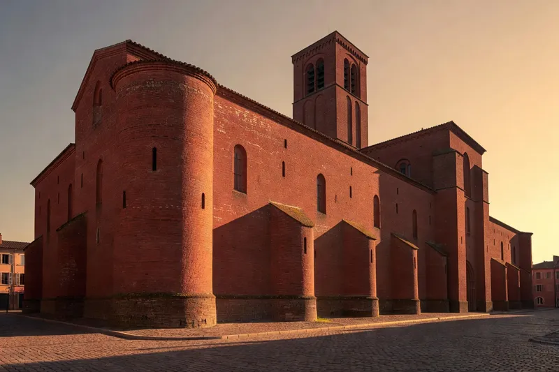 Imposante cathédrale médiévale de brique rouge, aux murs lisses et aux contreforts arrondis, dans l'esprit de Sainte-Cécile d'Albi.